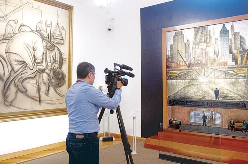 Un hombre grabando un cuadro en un museo