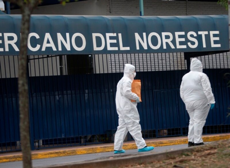 Dos personas con trajes de protección caminan por una calle vacía