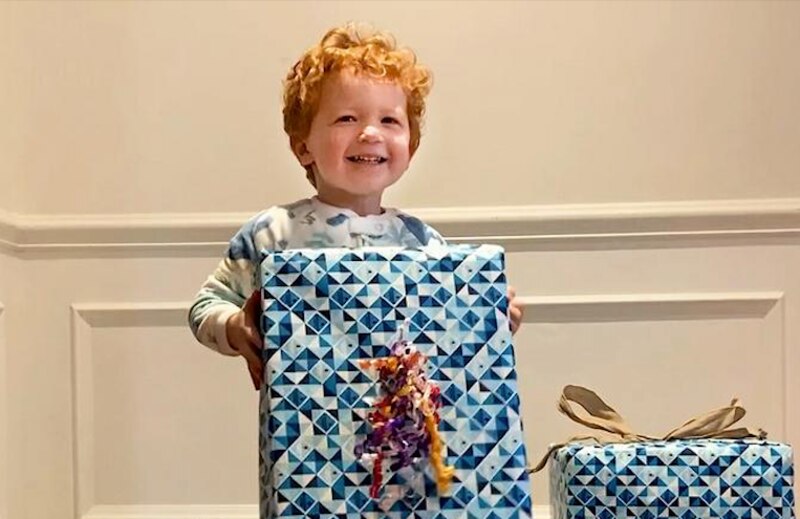 Niño pequeño sonriendo sosteniendo un regalo