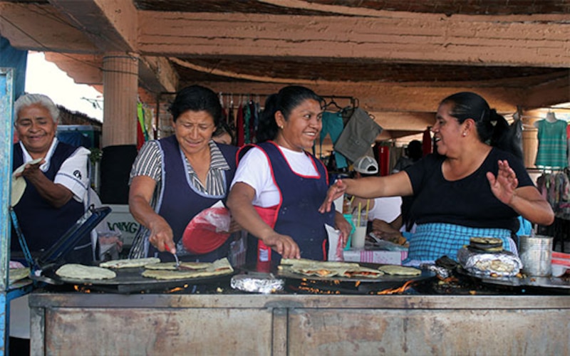 Mujeres indígenas preparando tortillas en un mercado mexicano