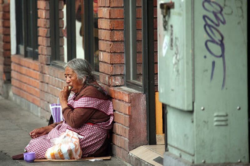 Anciana indigente sentada en la calle