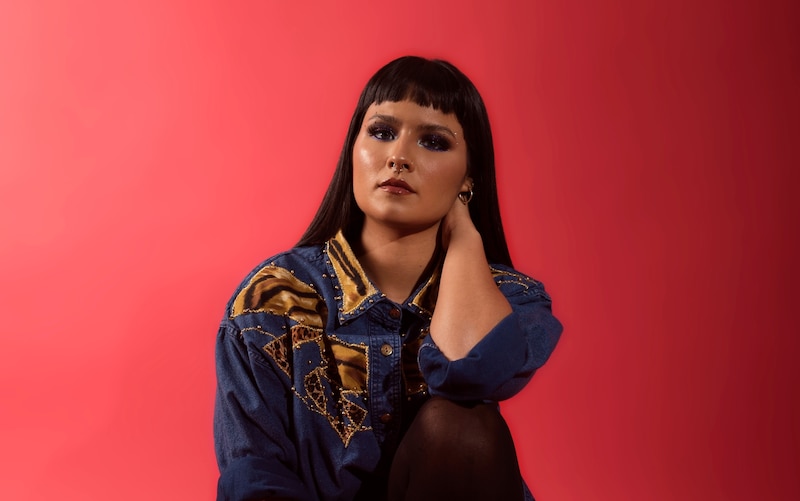 Mujer joven con camisa de mezclilla y maquillaje colorido