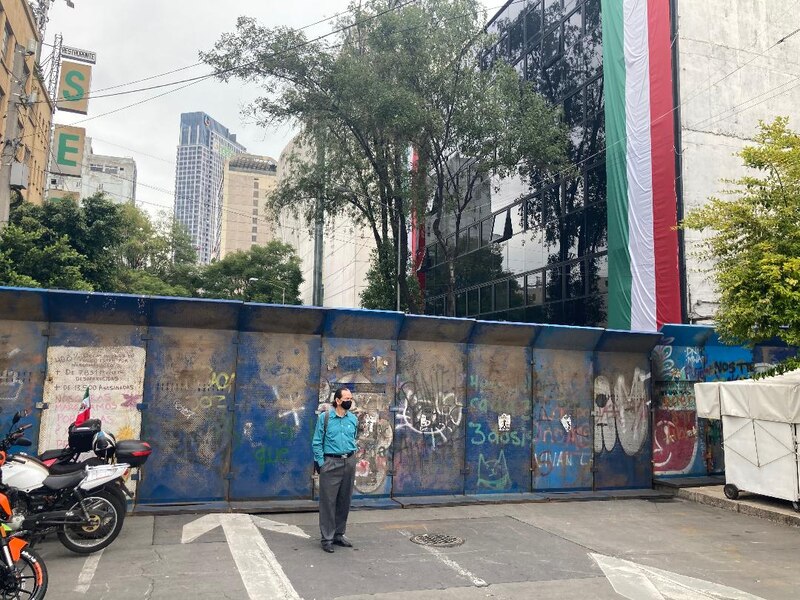 Un hombre con cubrebocas camina frente a una pared con grafitis