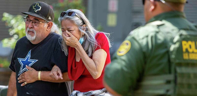 Un hombre y una mujer lloran mientras son escoltados por un agente de policía.