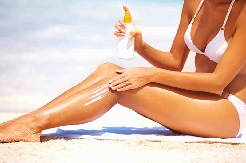 Mujer aplicándose protector solar en la playa