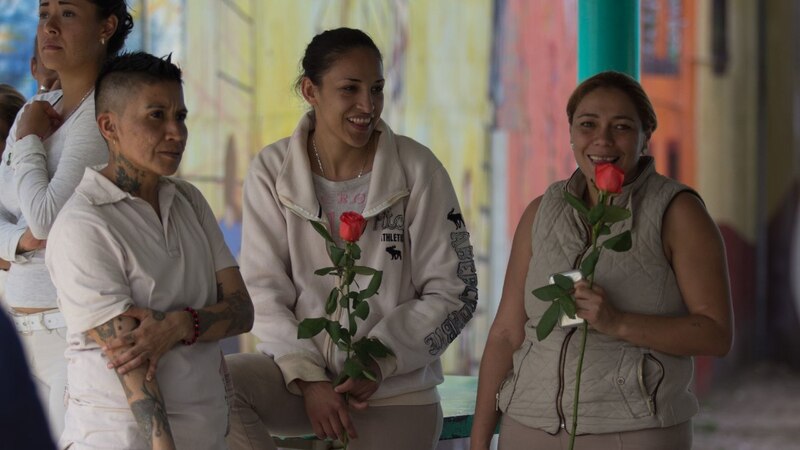 Mujeres sonríen y sostienen rosas
