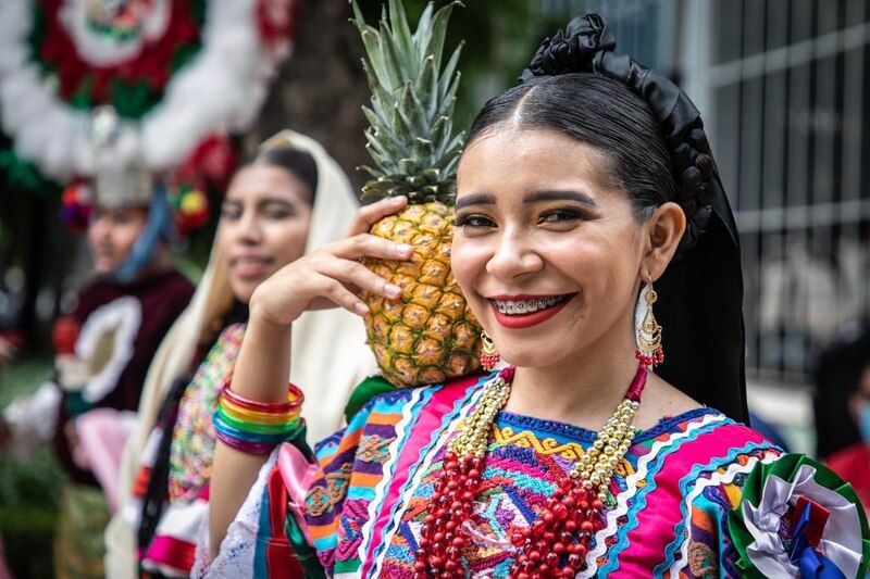 Mujer mexicana con traje tradicional y una piña en la cabeza