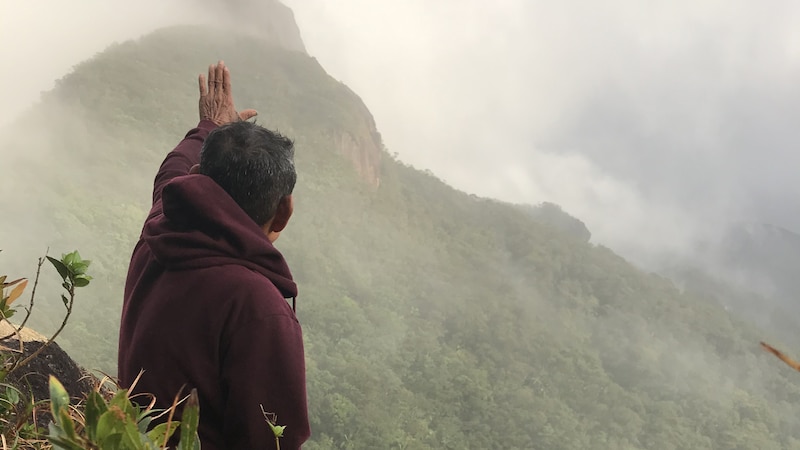 Hombre mirando al cielo en la cima de una montaña