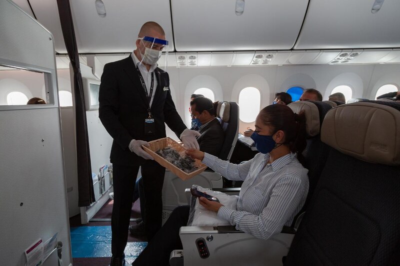 Azafato sirviendo comida a una pasajera en un avión