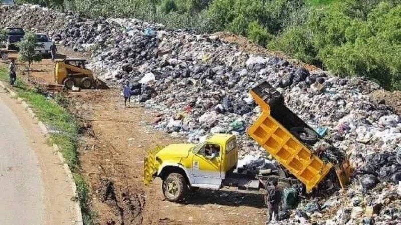Un camión de basura vierte residuos en un vertedero