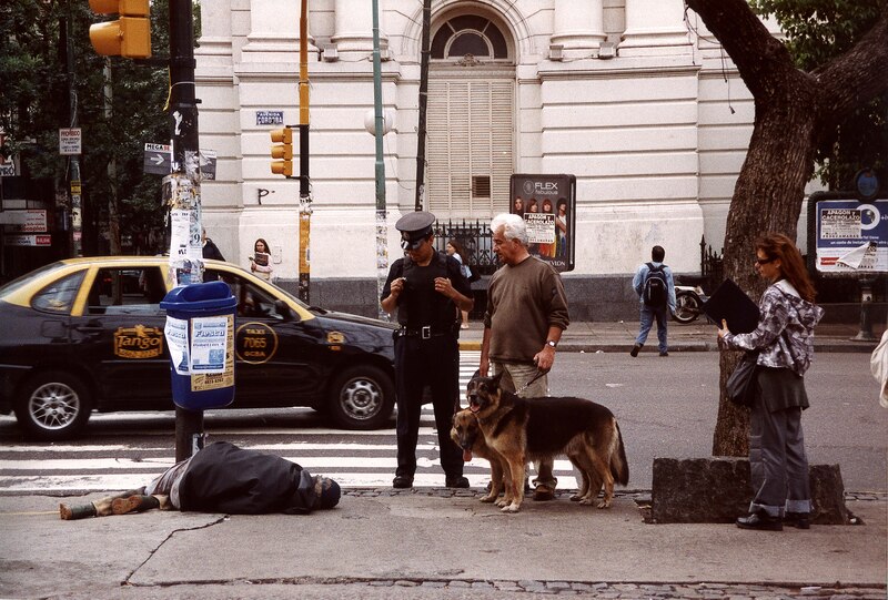 Un policía detiene a un hombre que pasea a sus perros mientras una mujer mira desde lejos