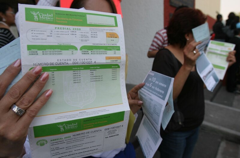 Title: Mujeres mostrando sus recibos de pago de impuestos prediales en México