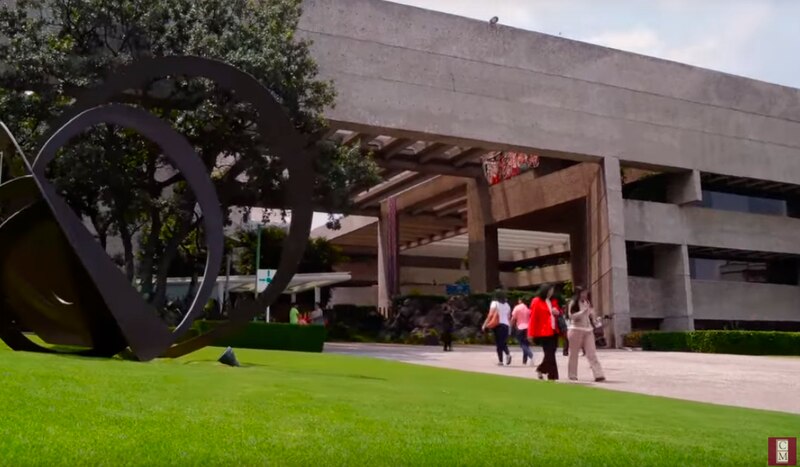 Edificio corporativo con un gran jardín y una escultura en primer término.