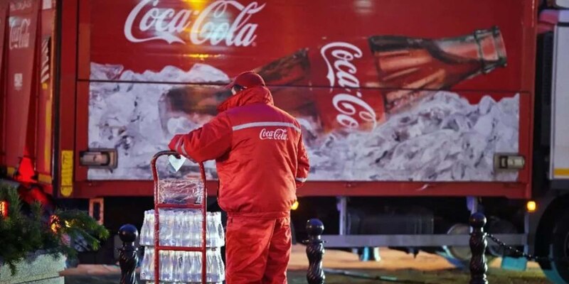 Un empleado de Coca-Cola entrega botellas de vidrio de la bebida a un local