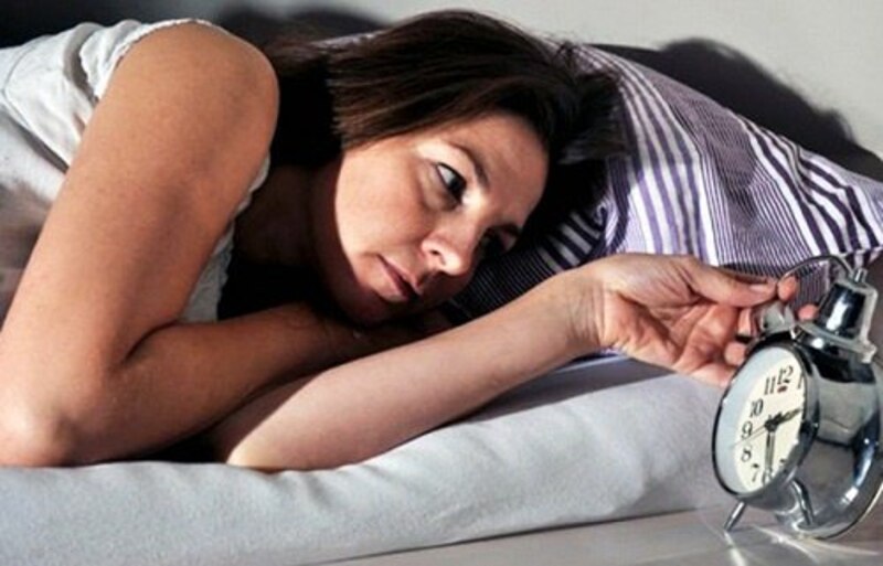 Mujer mirando el reloj en la cama