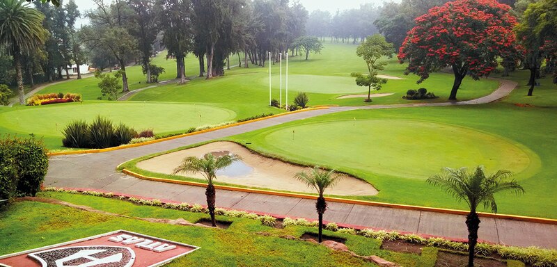 Campo de golf con árboles y un green en primer plano