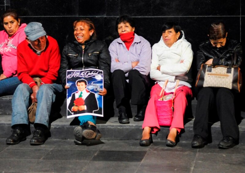 Mujeres indígenas esperan sentadas en una plaza
