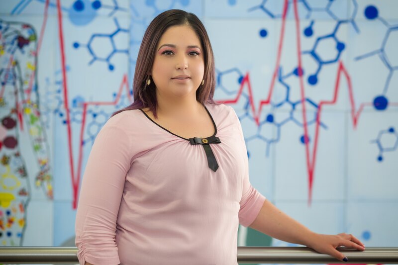 Mujer joven en bata de laboratorio frente a un gráfico científico