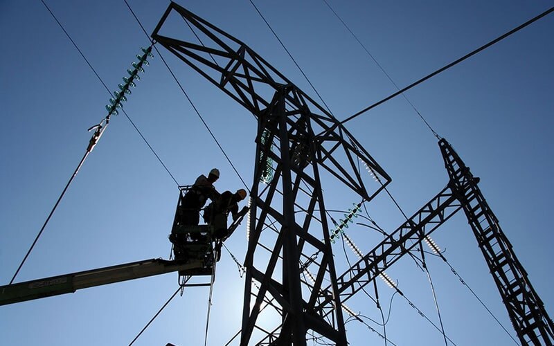 Dos trabajadores de la luz en lo alto de una torre de electricidad