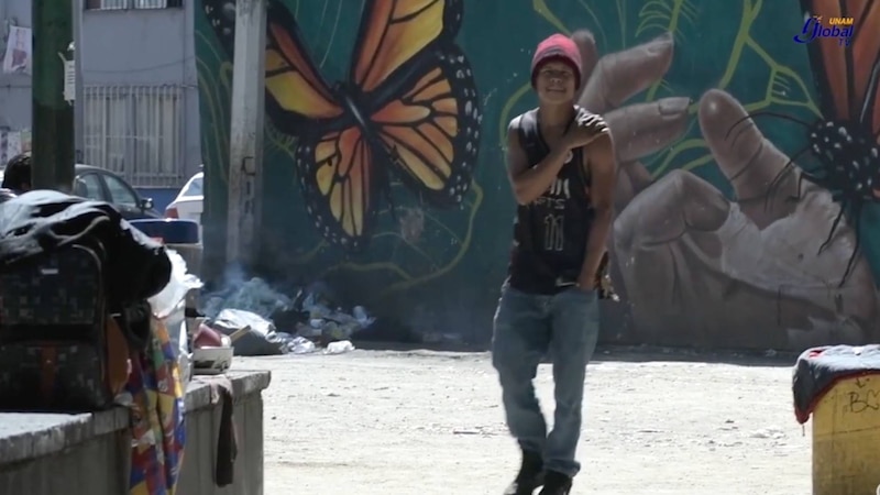 Adolescente sonríe frente a un mural de mariposas