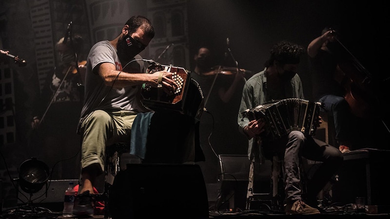 Dos hombres tocando el bandoneón en un escenario.