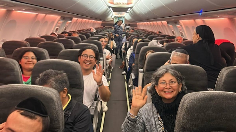 Pasajeros sonríen y saludan a la cámara en un avión