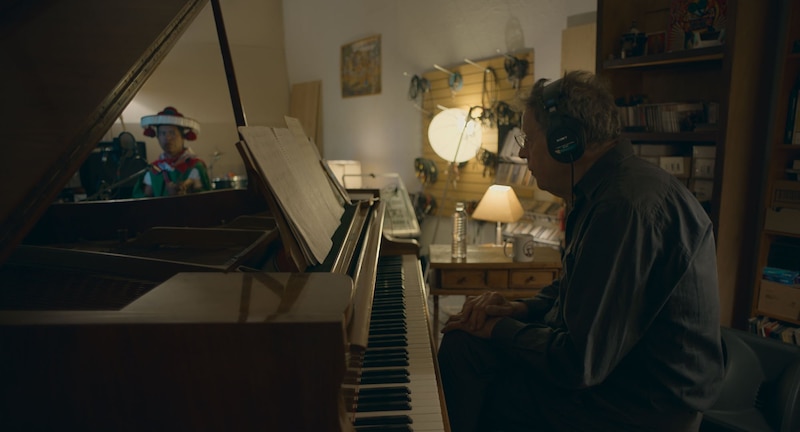 Un hombre tocando el piano en un estudio de grabación.