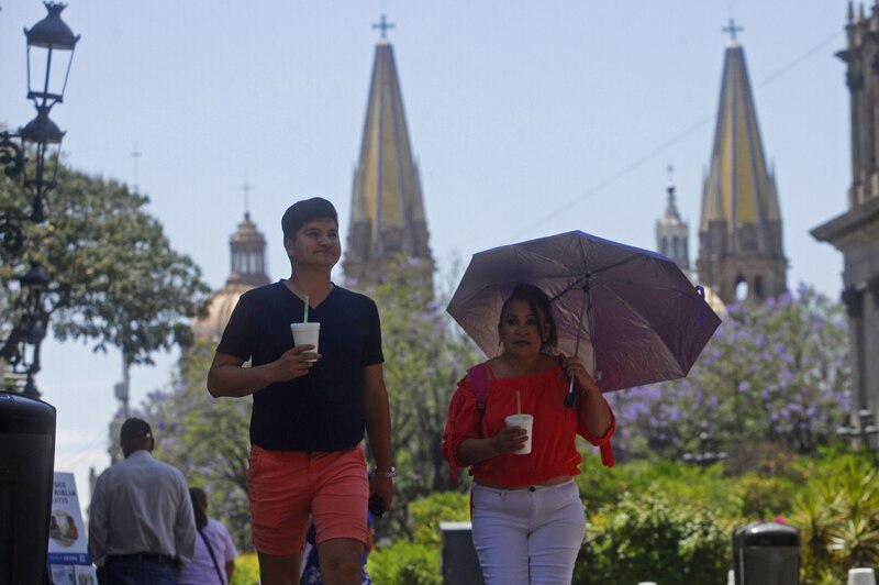 Una pareja camina por una calle de la Ciudad de México en un día soleado