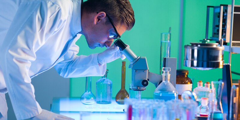 Científico mirando a través de un microscopio