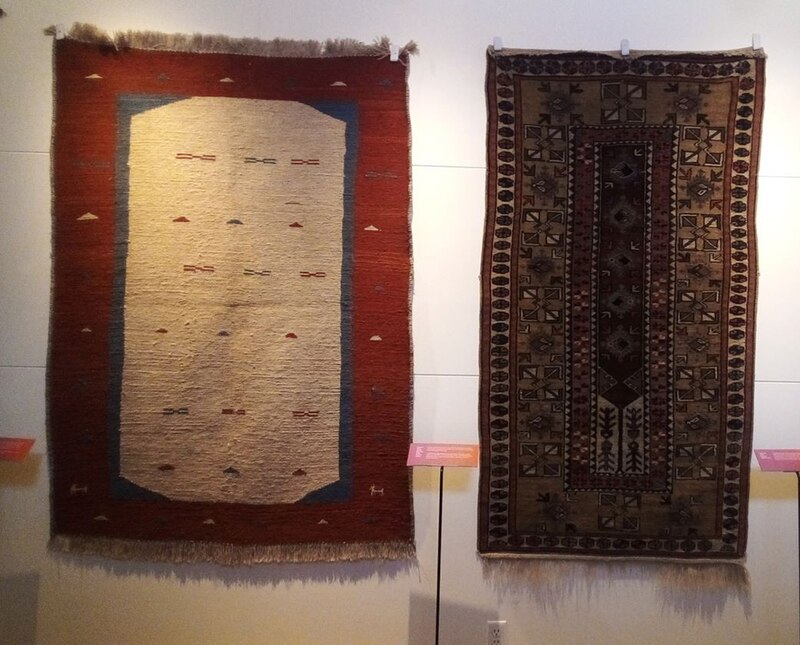 Dos alfombras antiguas cuelgan de una pared.