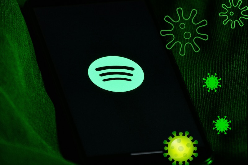 Dispositivo electrónico celular con el logotipo de Spotify en la portada y símbolos de virus a su alrededor