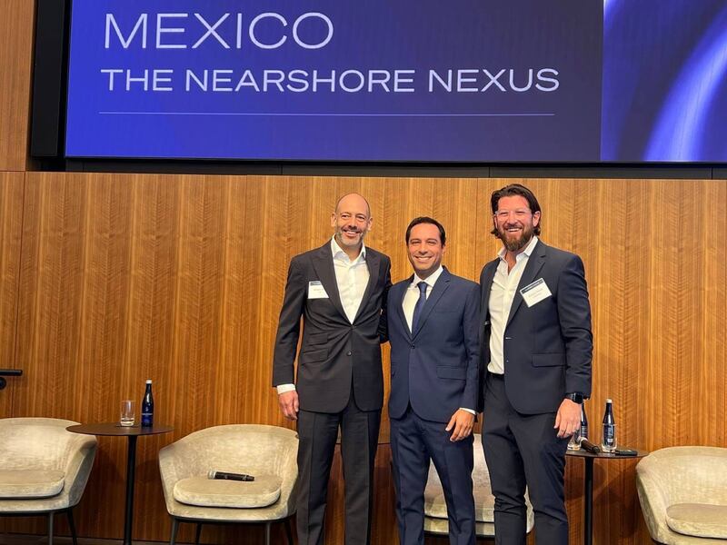 Tres hombres en traje sonríen y posan para una foto.