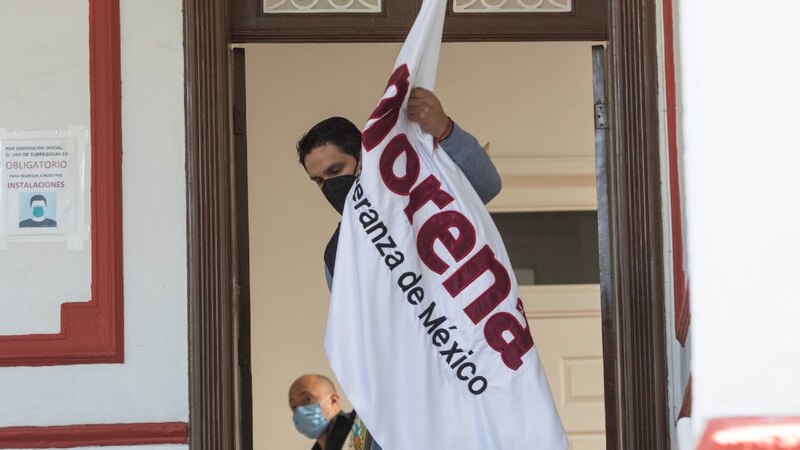 Un hombre sostiene una bandera de Morena