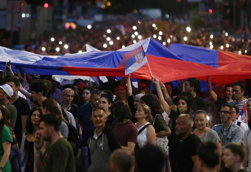 Multitud de personas ondeando banderas de Serbia