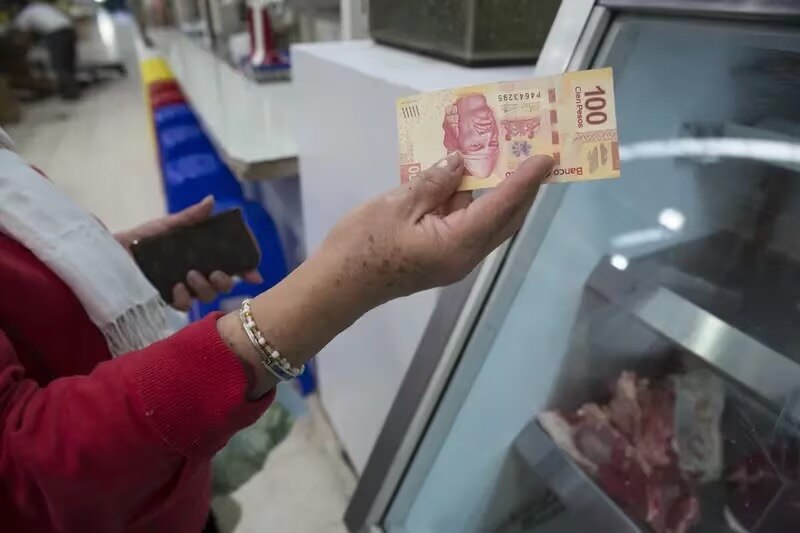 Mujer sosteniendo un billete de 100 pesos mexicanos