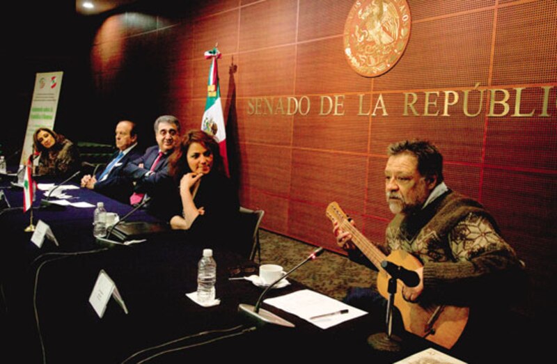 Senadores mexicanos escuchan atentos la canción de un músico durante un receso en la sesión.