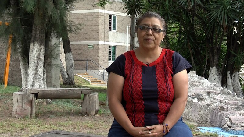 Mujer indígena sentada en un banco en un parque.