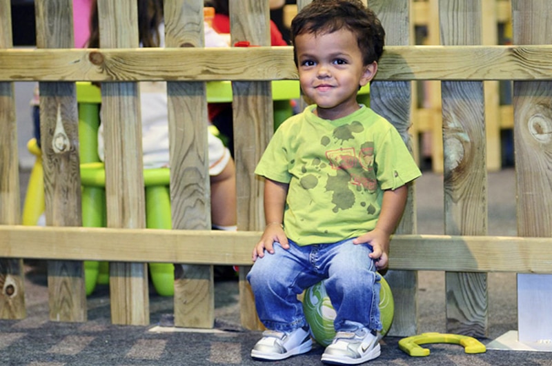 Niño sentado en una pelota verde