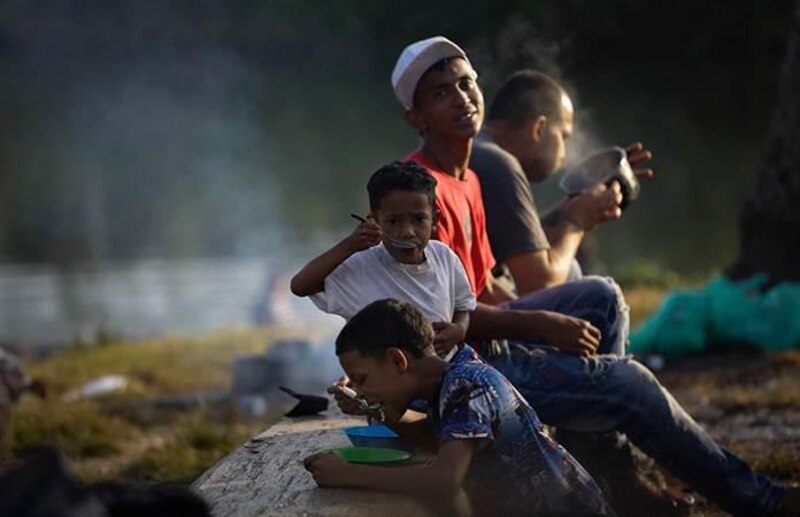 Niños migrantes comen en un campamento improvisado