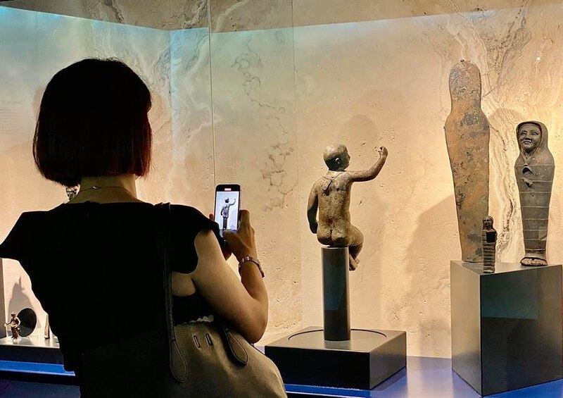 Mujer tomando una foto de una escultura en un museo