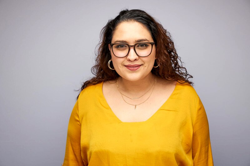 Retrato de una mujer joven con gafas y pelo rizado