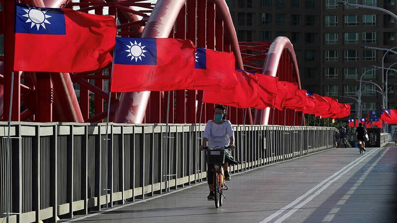 Mujer en bicicleta pasa por puente con banderas de Taiwán