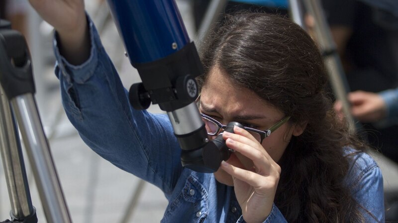 Mujer joven mirando por un telescopio