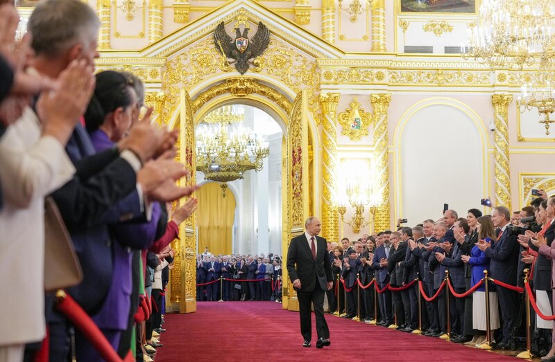 El presidente ruso, Vladimir Putin, camina por una alfombra roja mientras la gente aplaude.