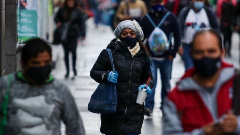 Mujer con cubrebocas caminando por la calle