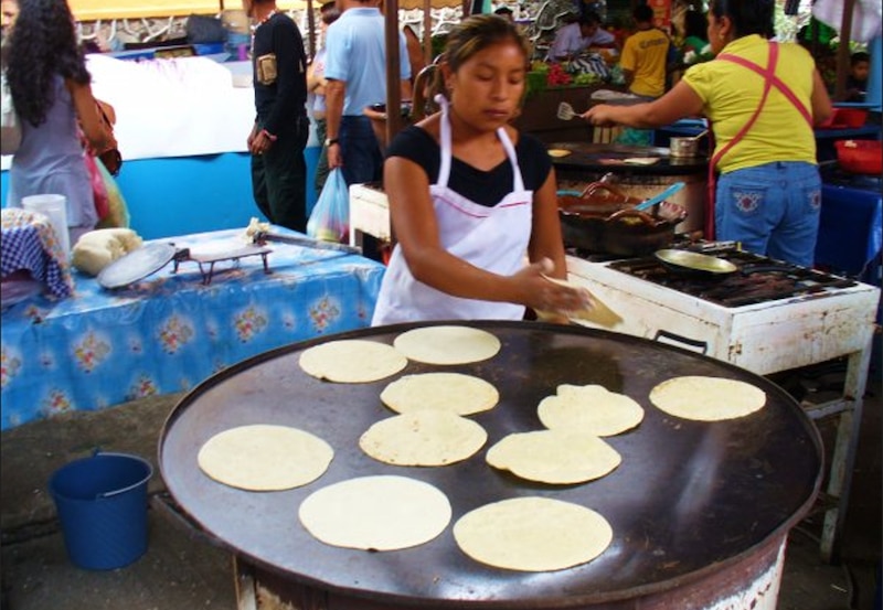 Mujer haciendo tortillas en un mercado mexicano