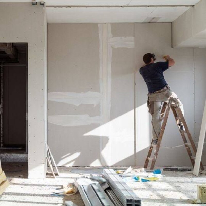 Hombre colocando paneles de yeso en una pared