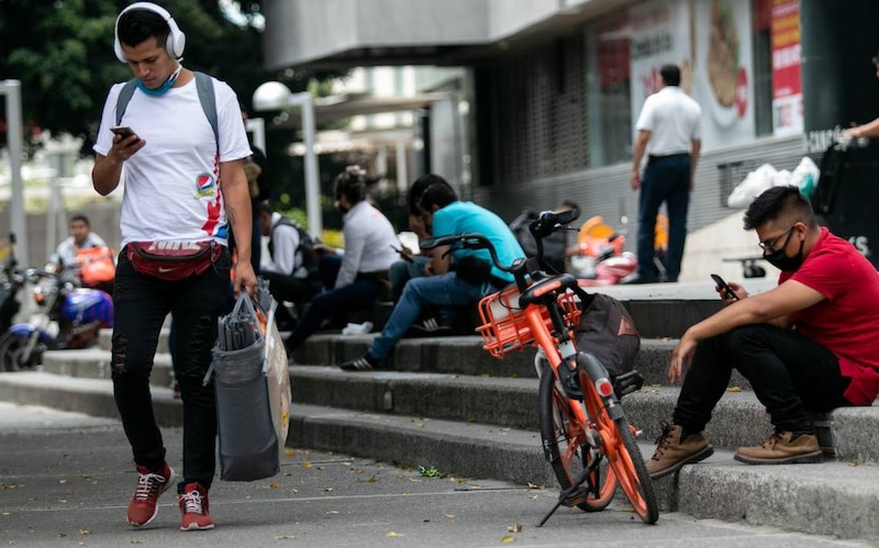 Jóvenes latinoamericanos usando sus teléfonos móviles en la ciudad