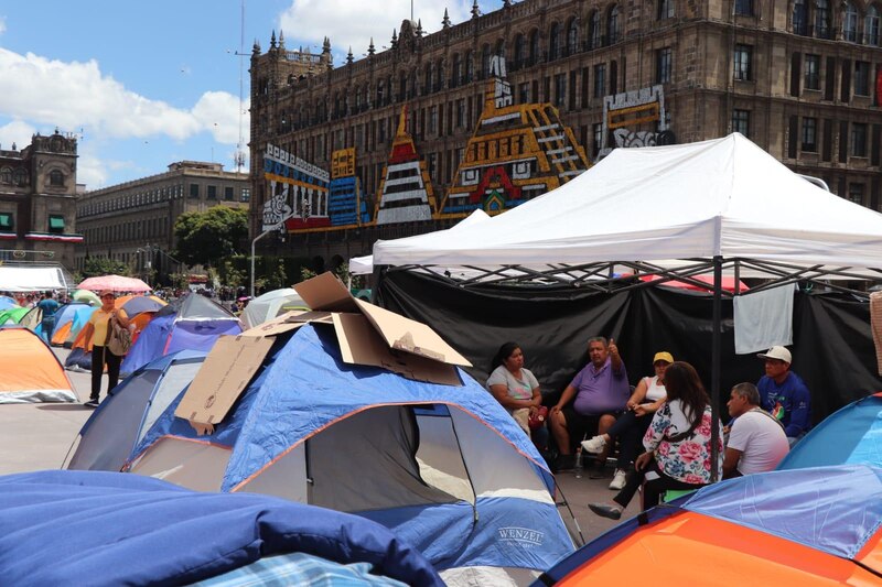 Un grupo de personas protesta acampando frente a un edificio gubernamental.