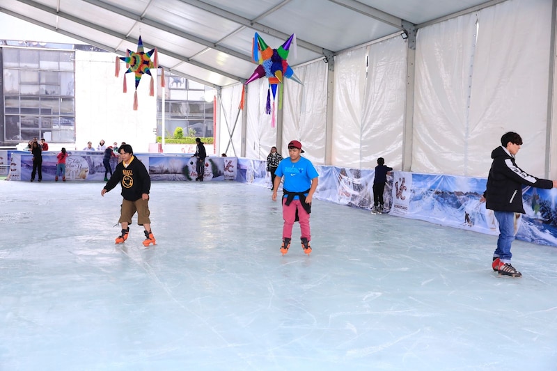 Jóvenes patinando sobre hielo en una pista de hielo cubierta